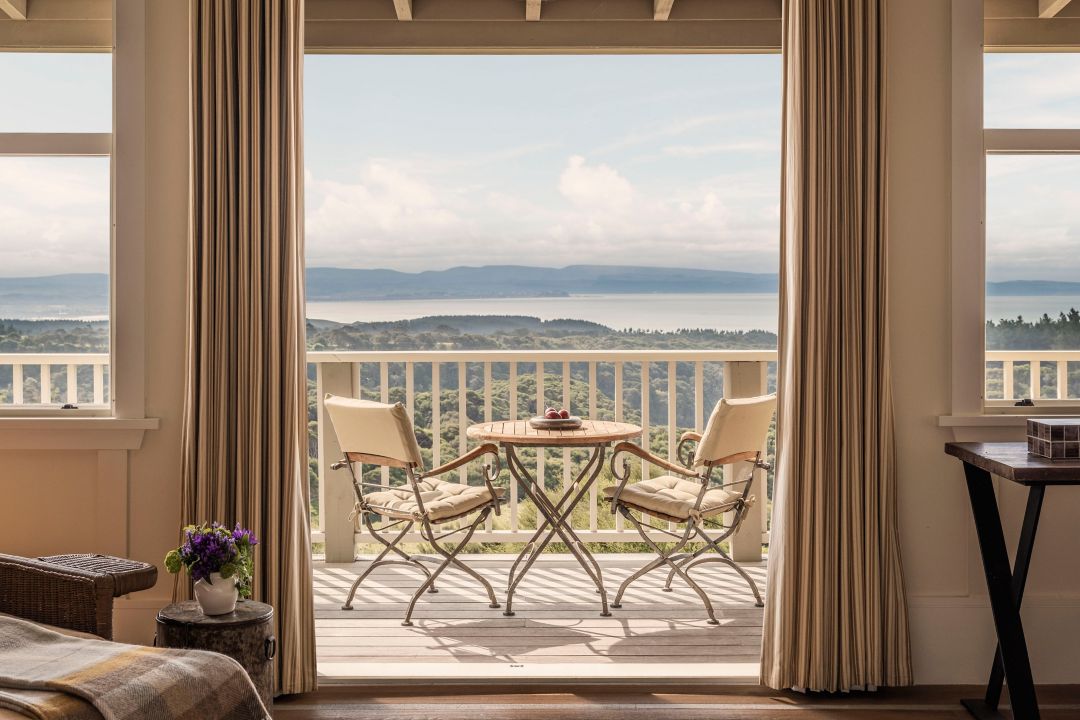 Living room in a luxury villa with barn doors, neutral furnishing, chandelier, large windows and farm views.
